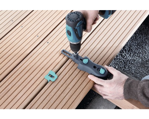 Osoba upevňuje terasové dosky pomocou skrutkovej svorky a akumulátorového skrutkovača