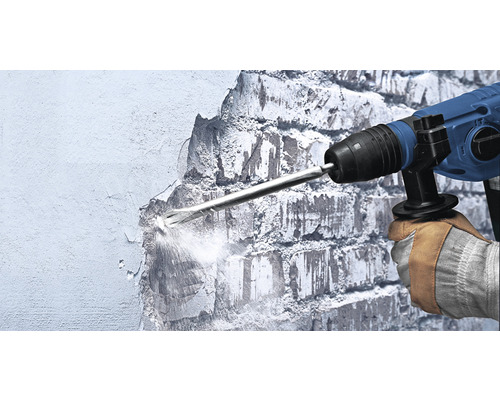 Pracovník používa demolačné kladivo na opracovanie steny.