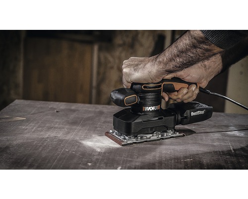 Osoba používa excentrickú brúsku WORX na drevenom povrchu.