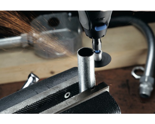 Potrubný zverák drží rúrku, zatiaľ čo ju multifunkčný nástroj opracováva a odletujú z nej iskry.