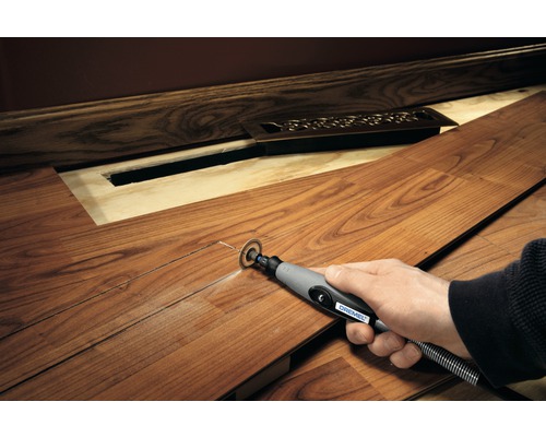 Osoba reže laminátovú dosku multifunkčným nástrojom Dremel, aby vytvorila priestor pre radiátor.