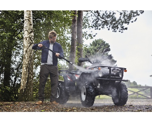 Muž čistí štvorkolku vysokotlakovým čističom vonku