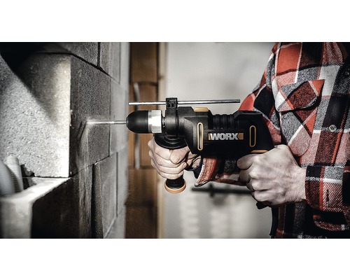 Osoba vŕta do tehlovej steny s príklepovou vŕtačkou Worx.