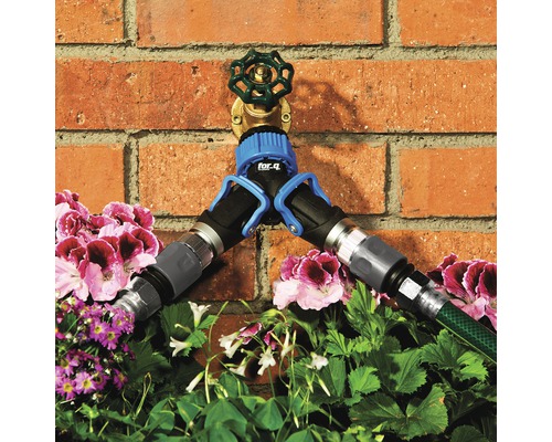 Vodovodný kohútik s rozdeľovačom a pripojenými záhradnými hadicami pred tehlovou stenou