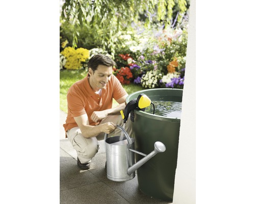 Muž plní kanvu čerpadlom na dažďovú nádrž v záhrade