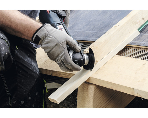 Osoba reže drevenú dosku multifunkčným nástrojom.