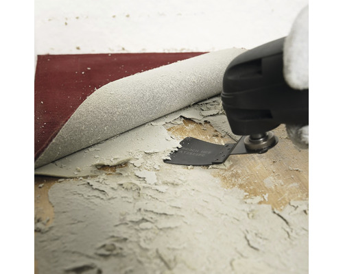 Oscilačný multifunkčný nástroj odstraňuje zvyšky lepidla z drevenej podlahy