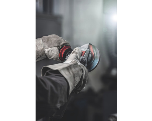 Muž s ochrannými rukavicami používa uhlovú brúsku.