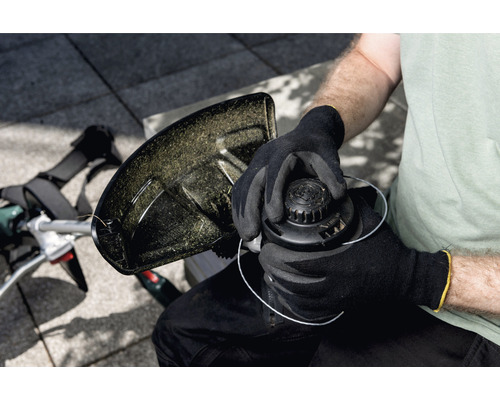 Osoba vymieňa cievku strunovej kosačky.