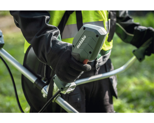 Osoba drží rukoväť vyžínača značky Metabo.