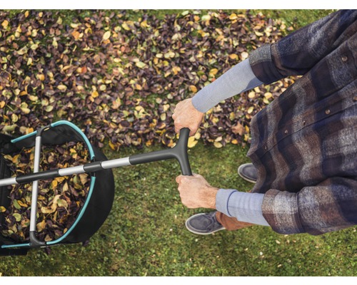Pohľad zhora na osobu s lapačom lístia na trávniku s jesenným lístím