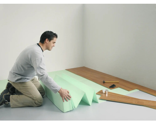 Muž pokladá laminátovú podlahu s kročajovou izoláciou