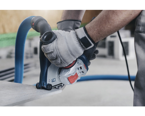 Drážkovacia fréza na steny pri rezaní kameňa, ovládaná osobou v rukaviciach.