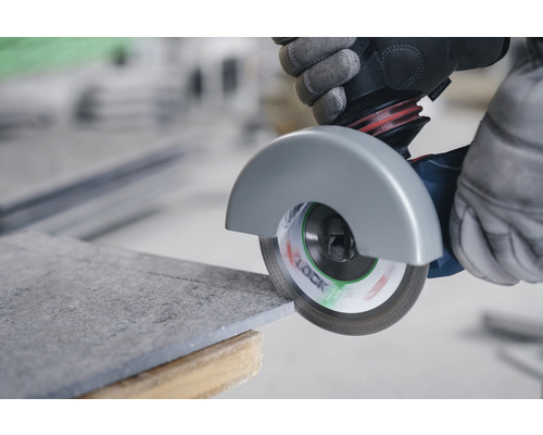 Dlaždica je rezaná uhlovou brúskou.