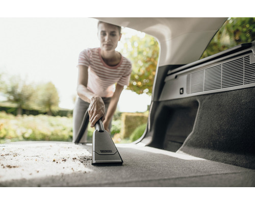 Žena vysáva kufor auta pomocou vysávača