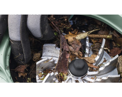 Detail rezacieho mechanizmu záhradného drviča so záhradnými rukavicami a lístím