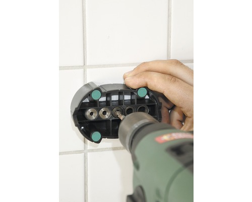 Vŕtačka vŕta cez vŕtaciu šablónu do obkladanej steny.