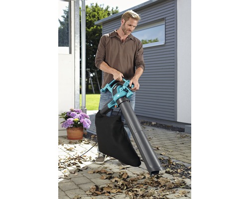 Muž používa vysávač lístia v záhrade.