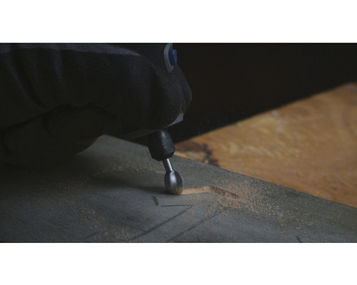 Osoba používa multifunkčný nástroj na vyrezávanie kusu dreva.