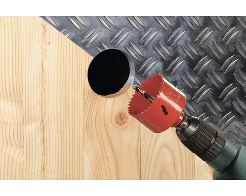 Dierovacia píla vŕta otvor do dreva pred kovovou doskou