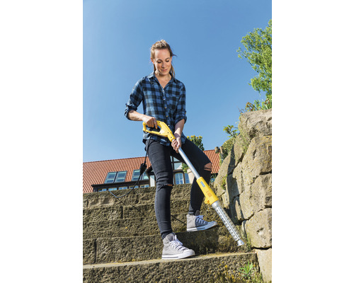 Žena odstraňuje burinu elektrickým odstraňovačom buriny na kamennom schodisku.