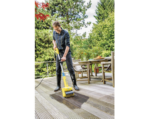 Muž čistí drevenú terasu čističom terás.