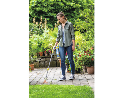 Žena používa plynový horák na ničenie buriny na terase.