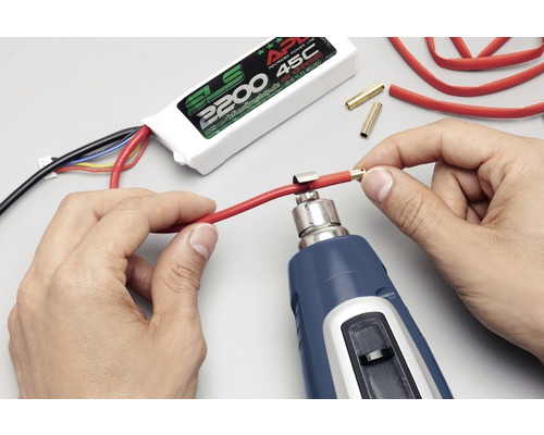 Osoba používa teplovzdušnú pištoľ na upevnenie konektora ku káblu. V pozadí je vidieť batéria SLS.