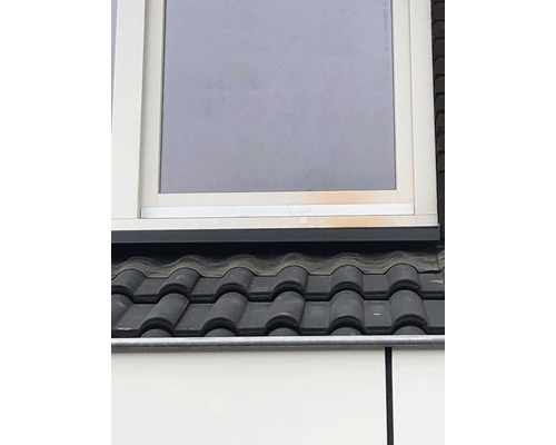 Detailný pohľad na strechu s škridlami a okno.