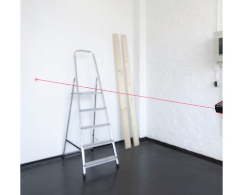 Miestnosť s rebríkom, drevenými doskami a laserovým diaľkomerom s červeným laserovým lúčom