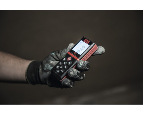 Ruka v pracovnej rukavici drží diaľkomer