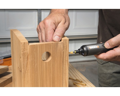 Osoba používa skrutkovač na zostavenie drevenej búdky pre vtáky.