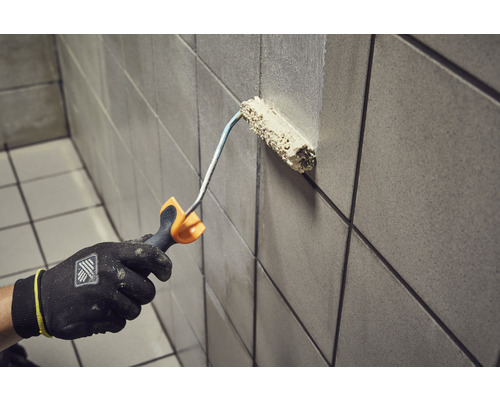 Osoba maľuje dlaždice valčekom.