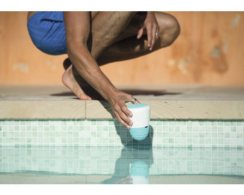 Osoba umiestňuje čistič bazéna do bazéna.