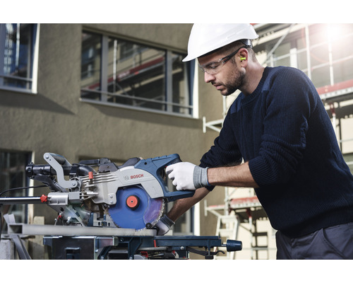 Muž s ochrannou helmou a okuliarmi obsluhuje pokosovú pílu Bosch.