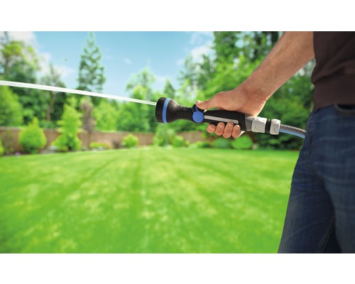 Osoba zavlažuje záhradu pomocou záhradnej striekacej pištole.