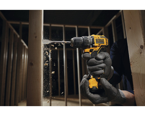 Osoba vŕta vŕtačkou DeWalt do dreveného rámu.
