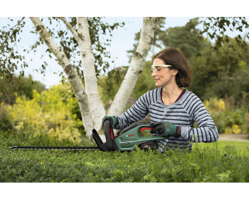Žena strihá živý plot pomocou akumulátorových nožníc na živý plot Bosch