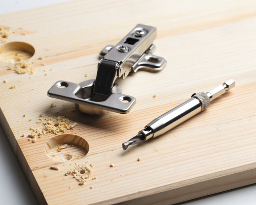 Nábytkový pánt, vrták do dreva a drevená doska s vyvŕtanými otvormi