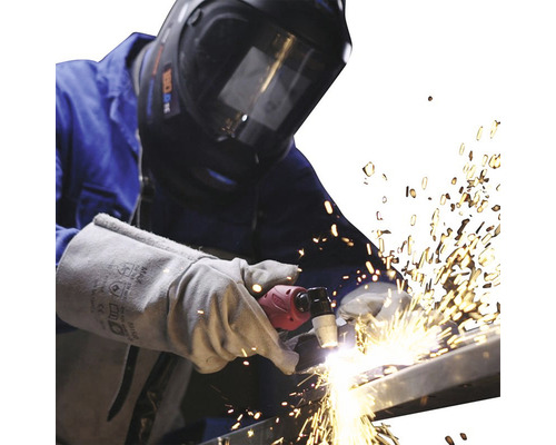Zvárač so zváračskou helmou a rukavicami plazmovo reže kov
