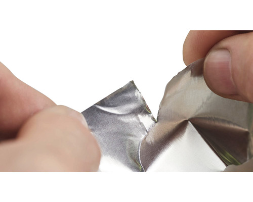 Ruky trhajú hliníkovú fóliu