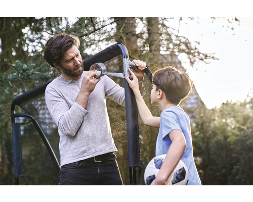 Otec a syn opravujú futbalovú bránku lepiacou páskou