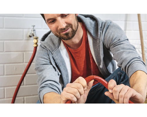 Muž drží netesnú vodnú hadicu