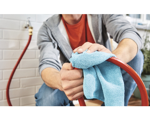 Osoba čistí hadicu handričkou.