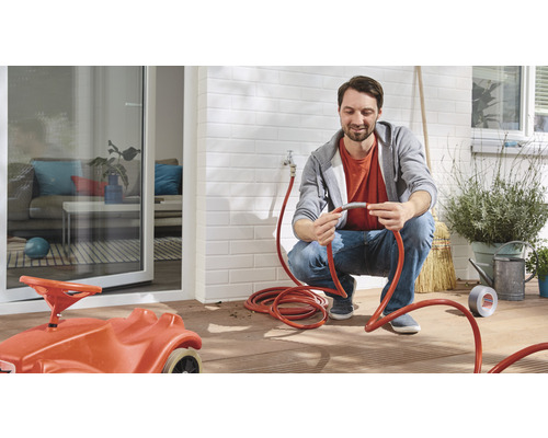 Muž pripája záhradnú hadicu na terase s detským hračkárskym autom.