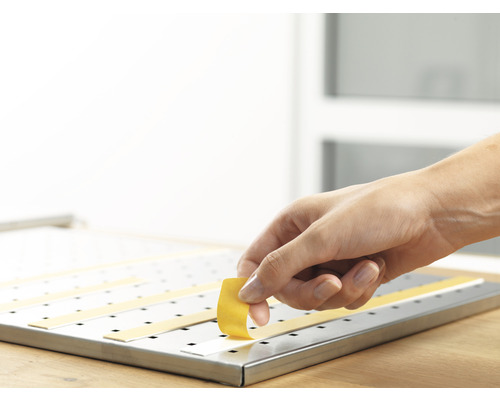 Ruka pripevňuje lepiacu pásku na kovový povrch.