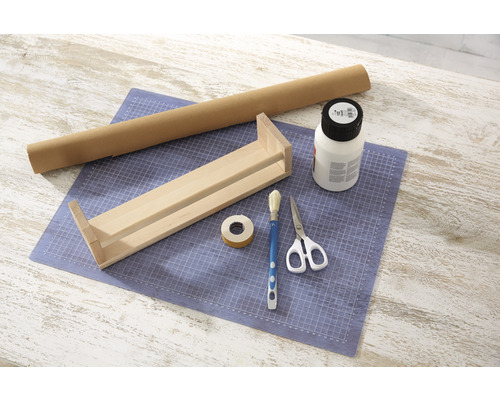 Pracovný stôl s drevenou policou, rolkou papiera, lepidlom, štetcom, lepiacou páskou a nožnicami