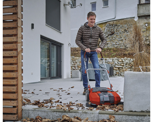 Muž používa vonkajší zametač na odstraňovanie lístia.