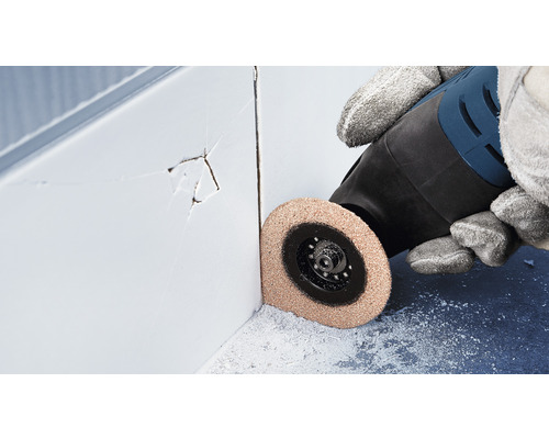 Osoba používa multifunkčný nástroj na odstránenie poškodených špár dlaždíc.