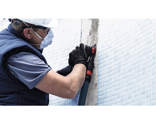 Remeselník s osobnými ochrannými prostriedkami pri spracovaní škár dlaždíc